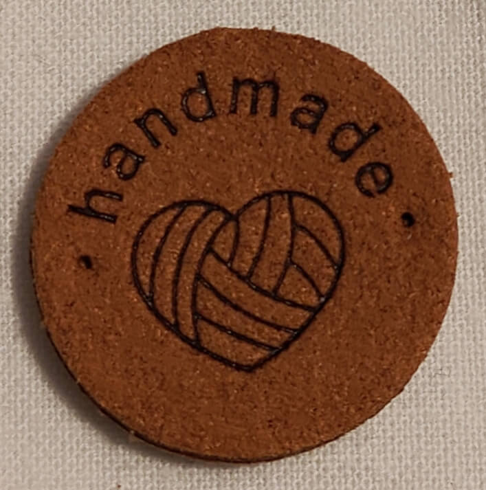 Keinonahkainen pyöreä ruskea handmade-merkki.
